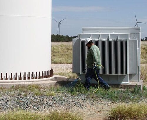 Applicator managing vegetation around renewable wind tower base.